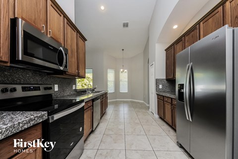 A kitchen with a stainless steel refrigerator and wooden cabinets.