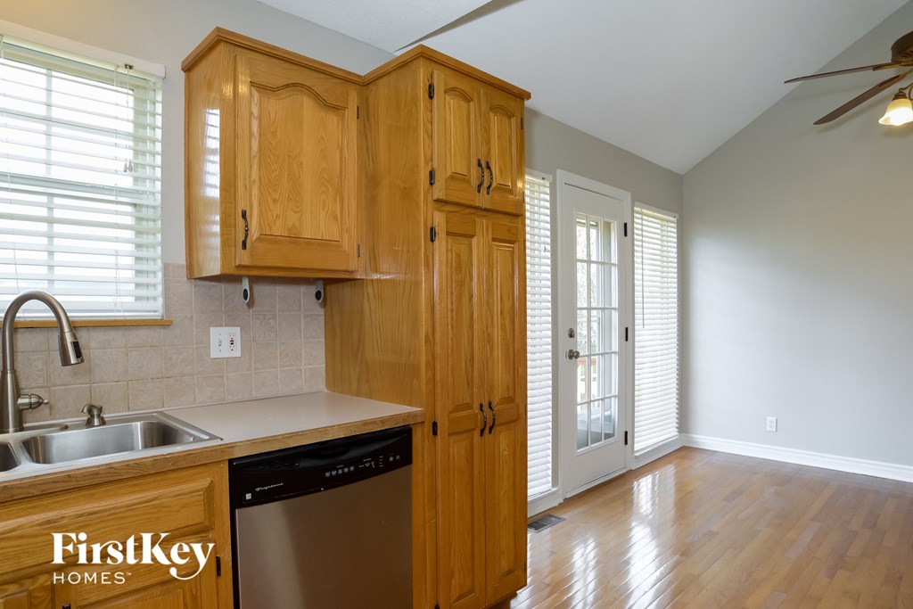 A kitchen with wooden cabinets and a stainless steel dishwasher.