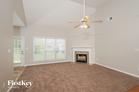 A spacious living room with a fireplace and a ceiling fan.