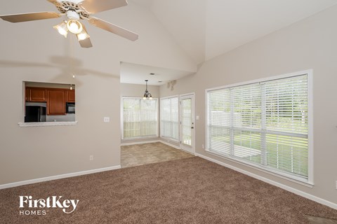A spacious room with a ceiling fan and a window with blinds.