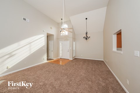 A spacious room with a carpeted floor and a chandelier hanging from the ceiling.