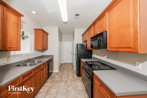 A kitchen with wooden cabinets and a black refrigerator.