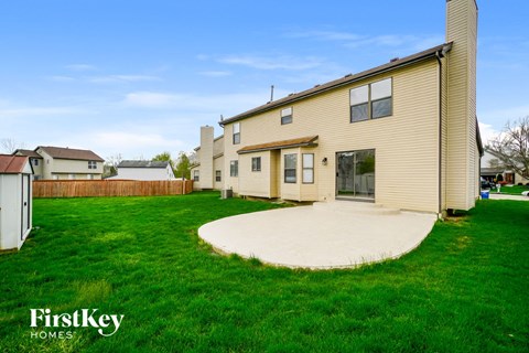a backyard with green grass and a house with a cement patio