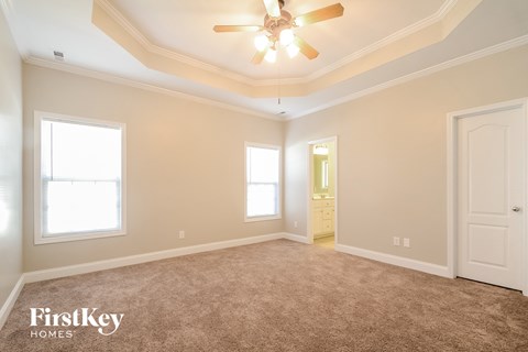 a master bedroom with carpet and a ceiling fan