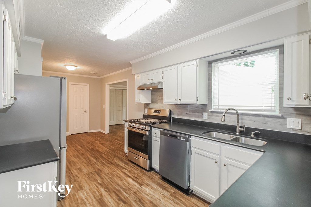 a kitchen with white cabinets and stainless steel appliances and a wood floor