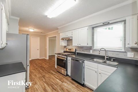 a kitchen with white cabinets and stainless steel appliances and a wood floor