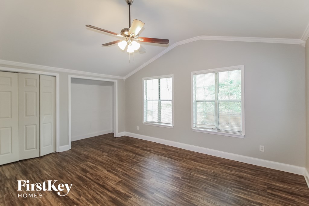 the living room of an empty house with a ceiling fan and windows