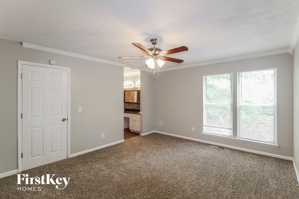 an empty living room with a ceiling fan and a kitchen