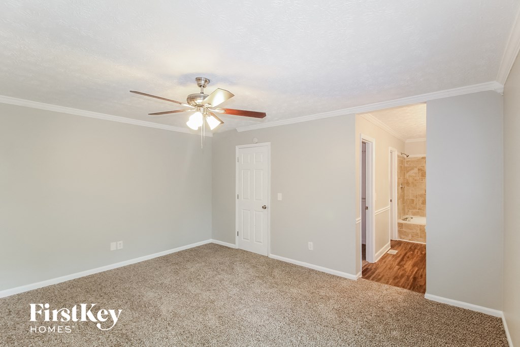 a bedroom with a ceiling fan and a door to a bathroom