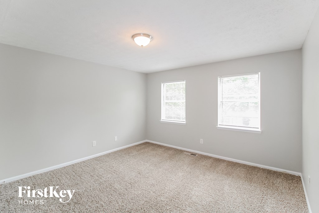 a bedroom with a carpeted floor and two windows