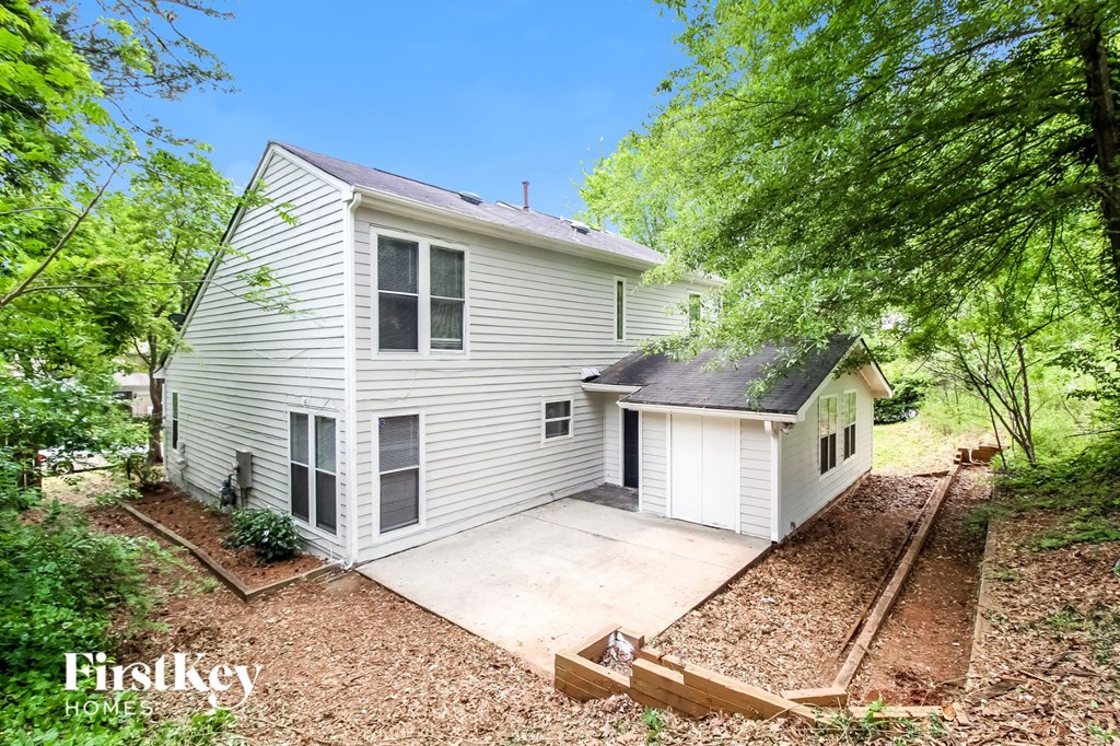 a white house with a driveway and a shed