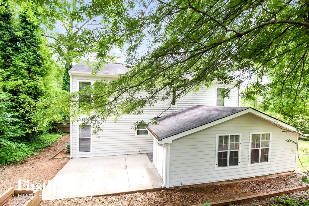 a small white house with a sidewalk and trees