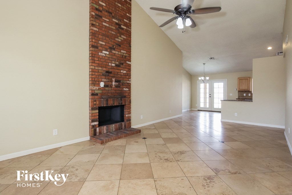 A room with a brick fireplace and a ceiling fan.