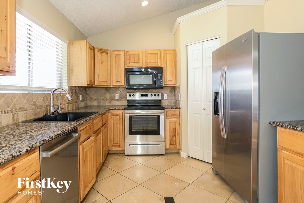 A kitchen with wooden cabinets and a stainless steel refrigerator.