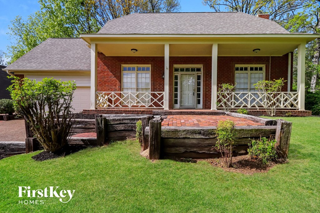 A house with a porch and a tree stump in the front yard.
