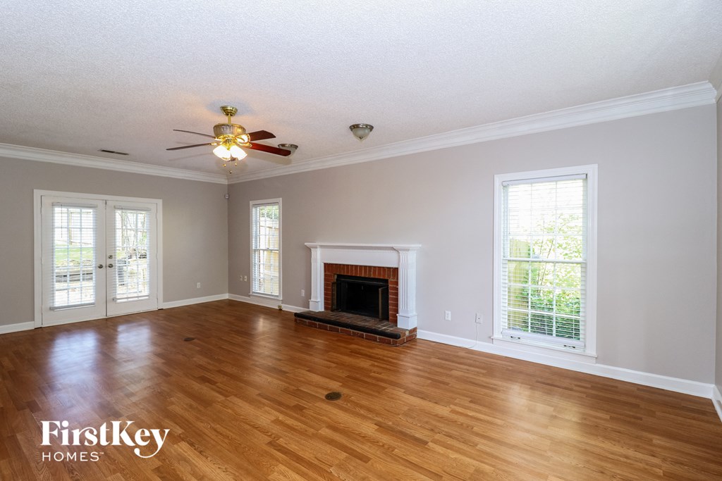 A spacious living room with a fireplace and a ceiling fan.