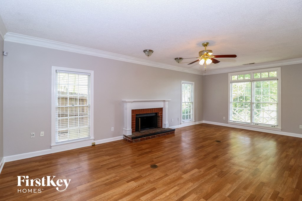 A spacious room with a fireplace and a ceiling fan.