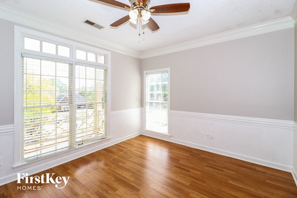 A room with a ceiling fan and wooden floors.