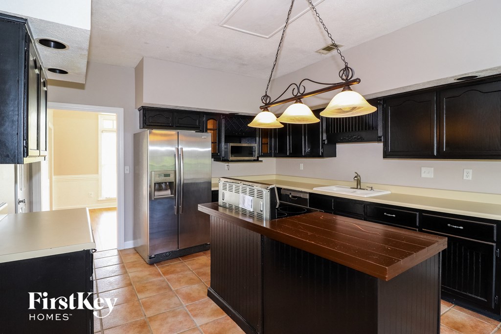 A kitchen with a wooden counter top and black cabinets.