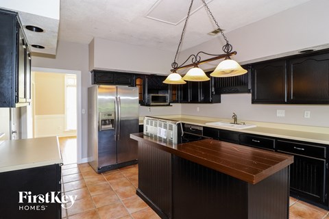 A kitchen with a wooden counter top and black cabinets.