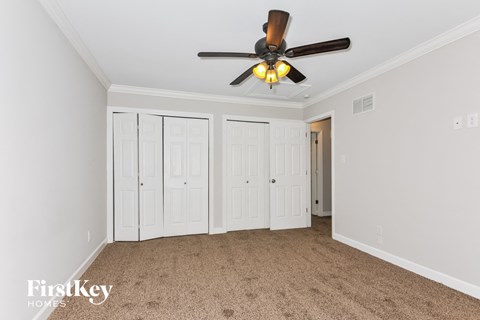a bedroom with white walls and a ceiling fan