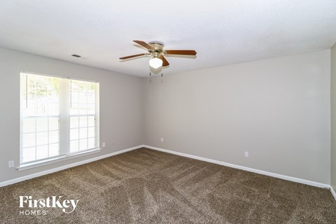 a living room with carpet and a ceiling fan