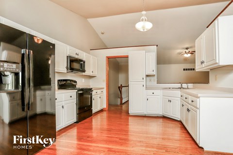 A kitchen with white cabinets and a wooden floor.