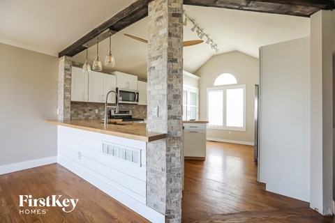 A kitchen with a stone pillar and wooden floors.