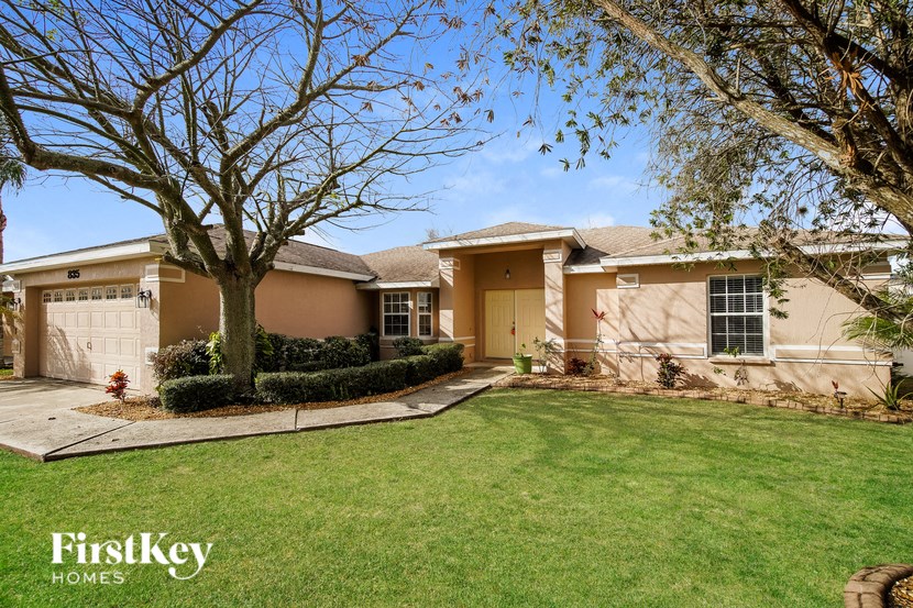 a beige house with a lawn and a tree