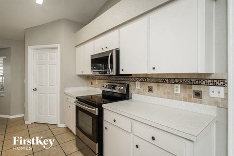 a kitchen with white cabinets and a stove and a microwave