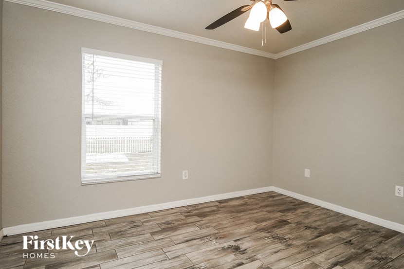 the spacious living room with wood flooring and a ceiling fan