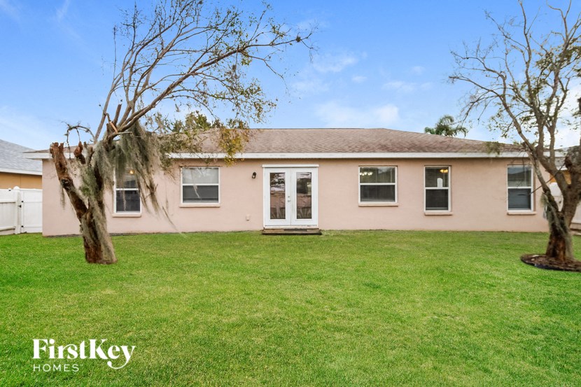a pink house with a lawn and two trees