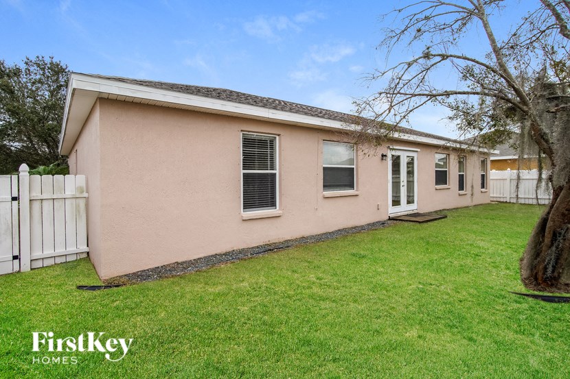 a small pink house with a yard and a white fence