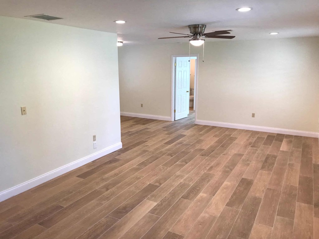 a empty living room with wood floors and a ceiling fan