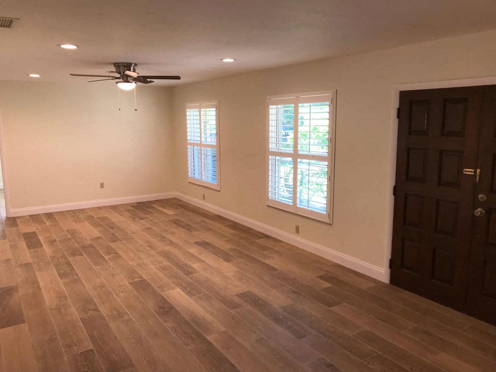 an empty living room with wood floors and a ceiling fan