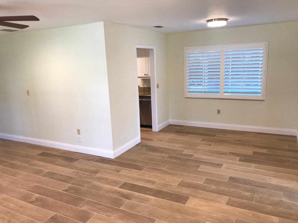 an empty living room with wooden floors and a window