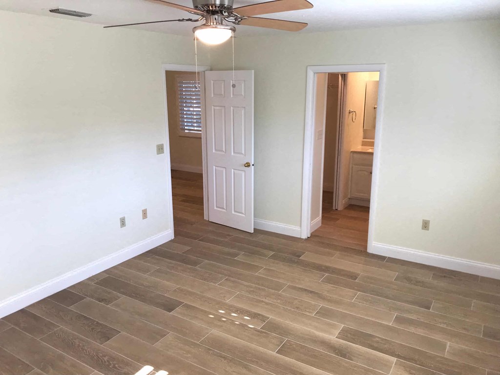 an empty living room with a ceiling fan and tile floor