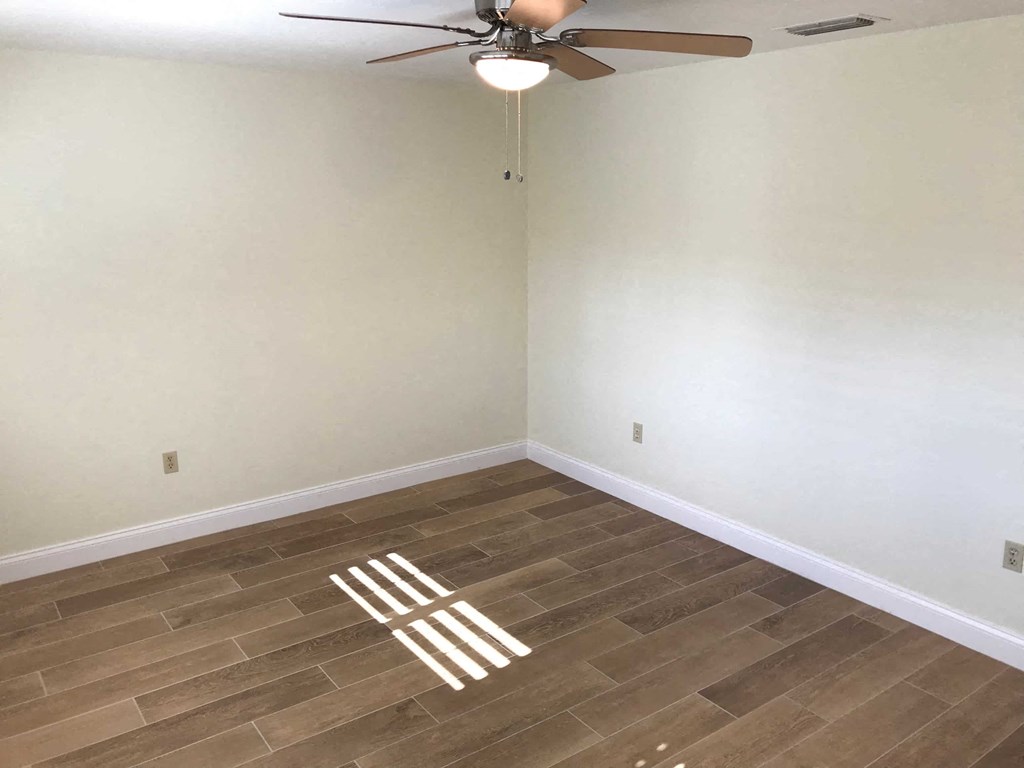 a empty room with a ceiling fan and wood floors