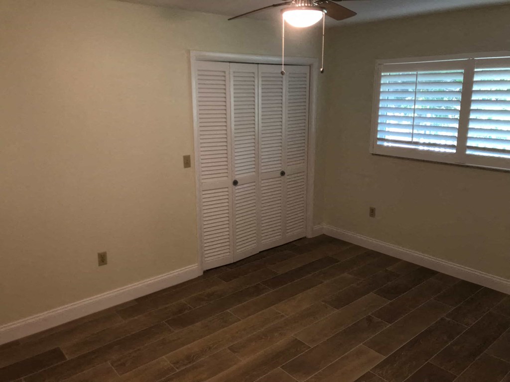 a bedroom with a closet and a wood floor