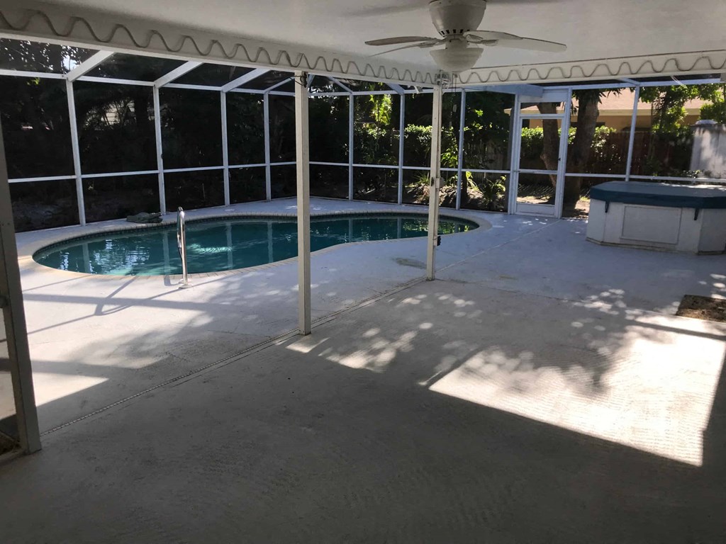 a patio with a swimming pool and a porch with a ceiling fan