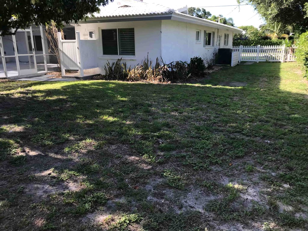 the front yard of a house with grass and a white fence