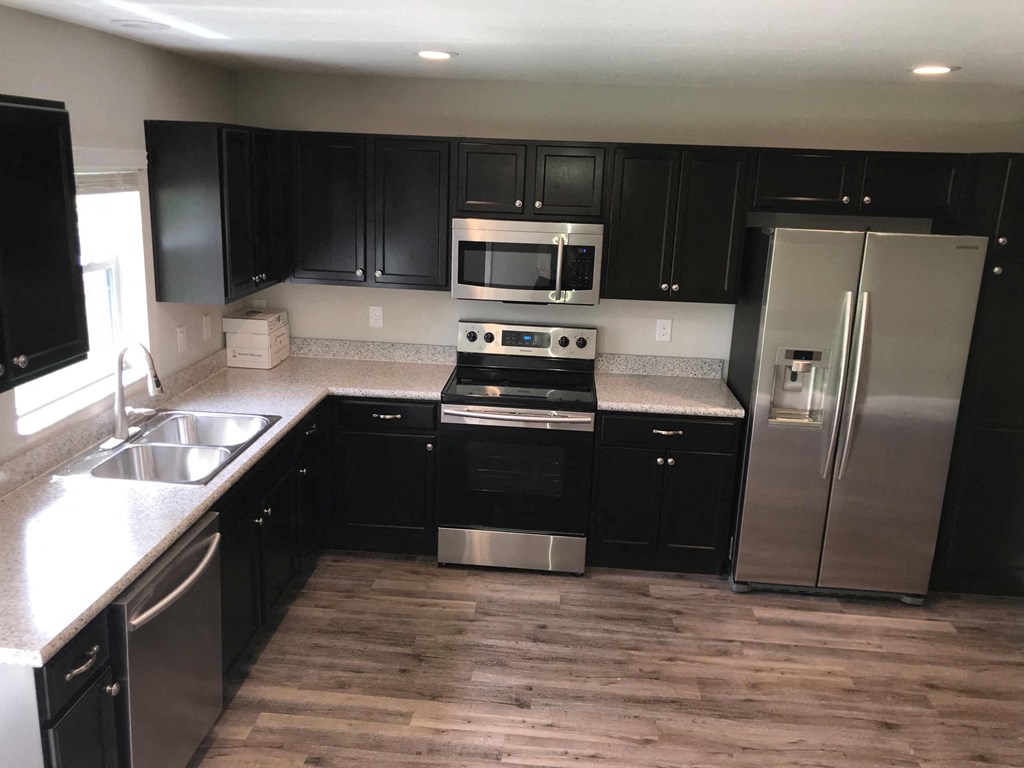 A kitchen with black cabinets and stainless steel appliances.