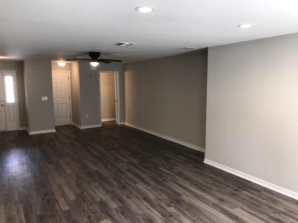 A room with a ceiling fan and wooden flooring.