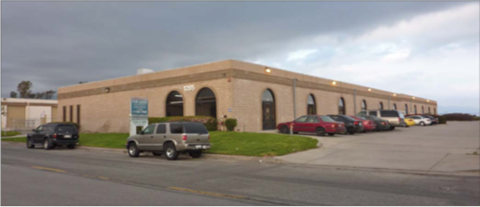 A parking lot in front of a building with cars parked.