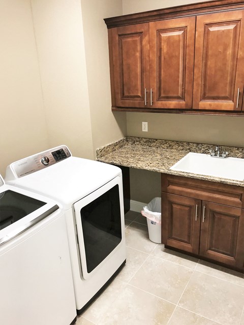 a kitchen with a washer and dryer in it and wooden cabinets