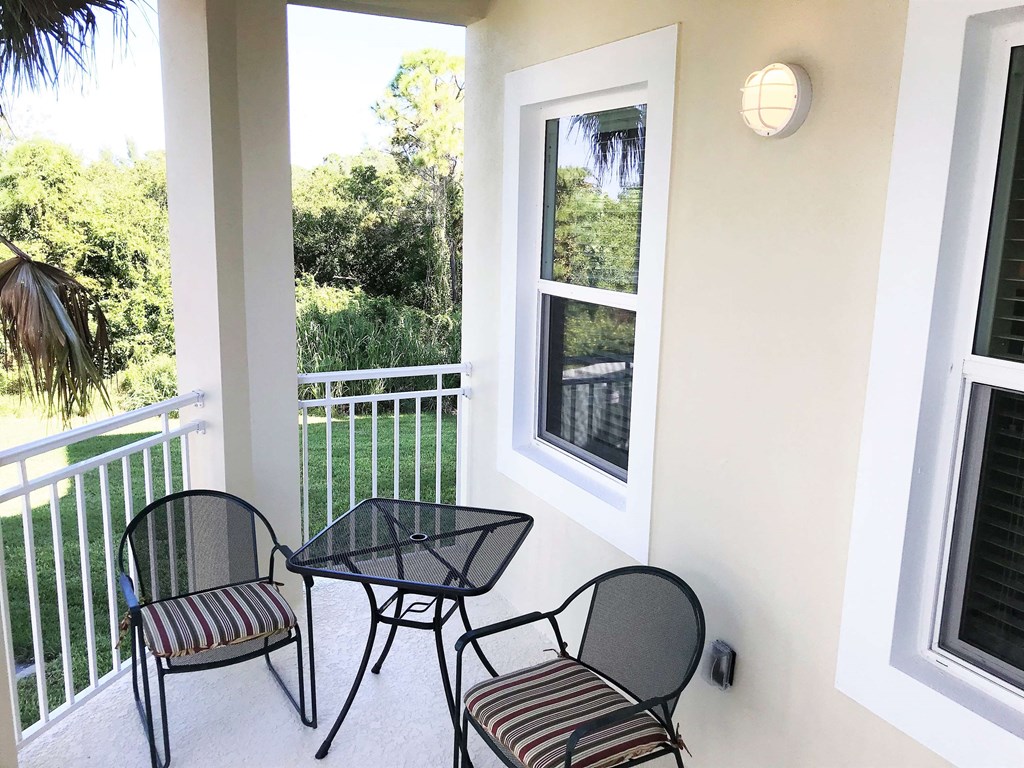 a balcony with two chairs and a table and a window