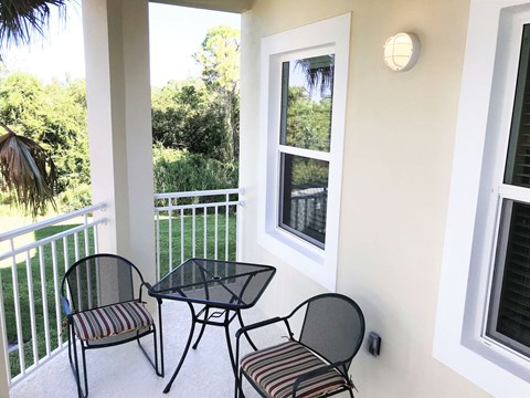 a balcony with two chairs and a table and a window