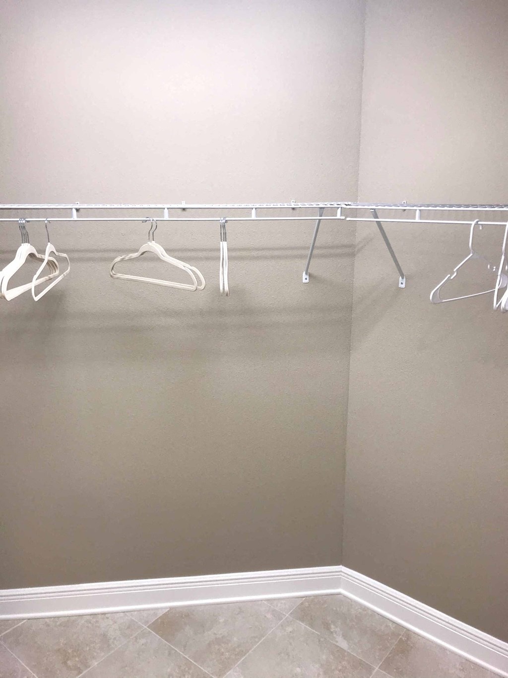 a walk in closet with clothes hangers on a rack