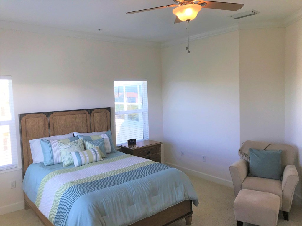 a bedroom with a bed and a chair and a ceiling fan