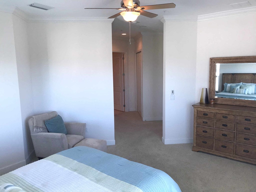 a bedroom with a bed and a dresser and a ceiling fan